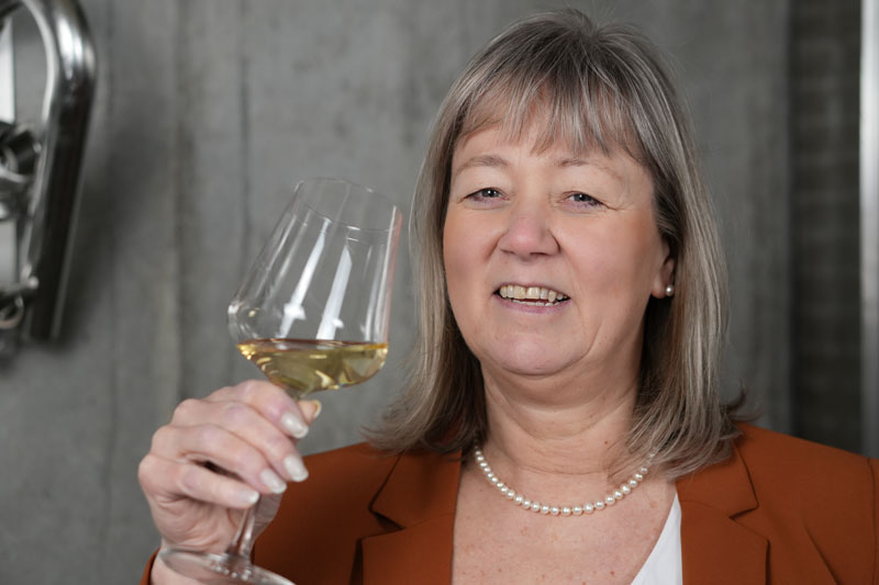 Beate Groiß lächelnd in die Kamera schauend und ein Weinglas hoch haltend
